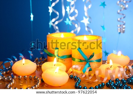 Beautiful candles, gifts and decor on wooden table on blue background