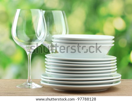 Clean dishes on wooden table on green background
