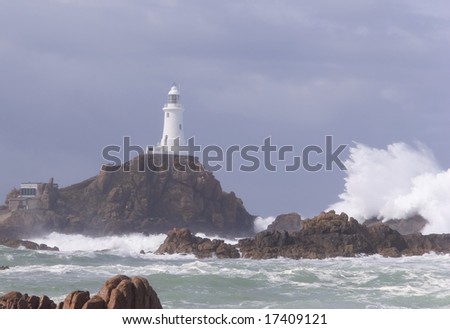 A large wave crashes over rocks at Corbiere lighthouse, Jersey