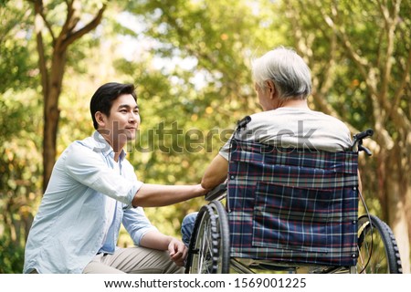 asian son talking to and comforting wheelchair bound father Foto d'archivio © 