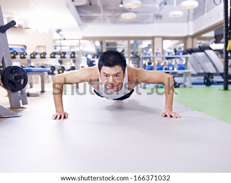 man doing push-ups on gym floor.