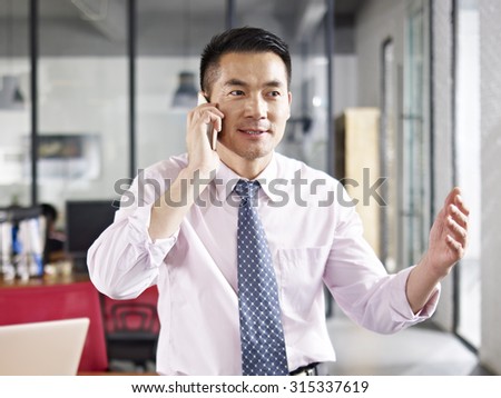 asian business person talking on cellphone in office.