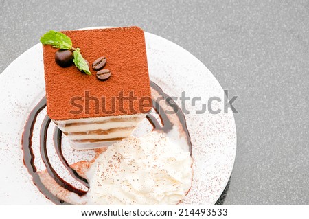 Vanilla ice cream with whipped cream and Ovaltine powder and coffee beans on a dessert on a plate.