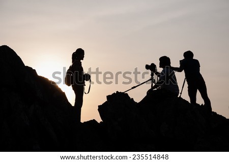 Stylish silhouette image of many photographers on the rocky hills.