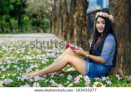 Young christian woman reading a bible under pink flower tree