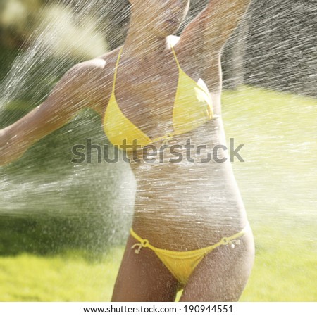 Spray water on a female body with yellow bikini