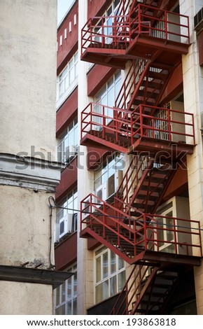 Red emergency staircase in a building facade. Vertical