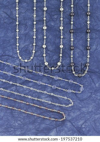 Silver necklaces over a blue background. Vertical format