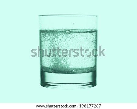 Glass of water with effervescent tablet in green tone