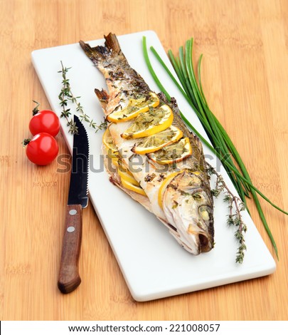 grilled sea bass with lemon thyme cherry tomatoes on a wooden board