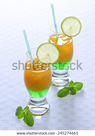 Dual Layer summer cocktail mint liqueur orange and lime on a blue background