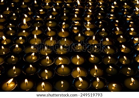 Lighted candles lined up in a row and glow in the dark space. Monastery in Nepal. Tibet, the Himalayas.