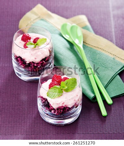 healthy breakfast oatmeal with raspberries mint yogurt in a glass cup on a purple background with green spoons