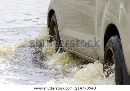 Car splashes through a large puddle on a flooded street