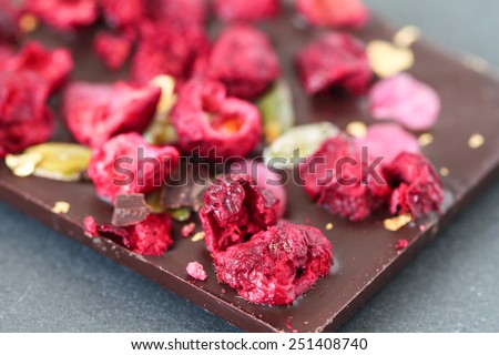 Dark  chocolate bar with berry fruits, rose petals, pistachios and gold powder