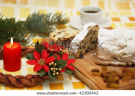 Christmas cake and advent wreath with candle and cup of coffee at back