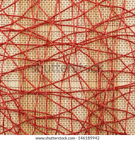 Bamboo mat covered with the red threads as abstract background composition