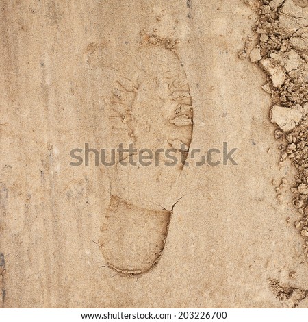 Shoe step left in the sand as an abstract background composition