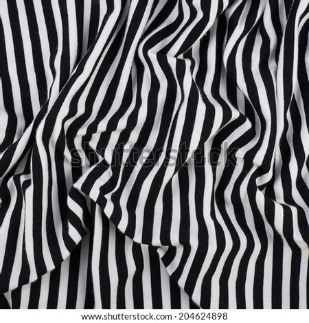 Fragment of a striped wrinkled black and white piece of a cloth fabric as a background texture