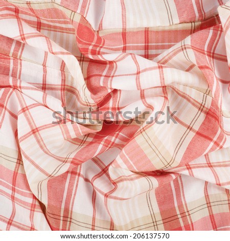 Fragment of a wrinkled red and white squared cloth fabric as a background texture
