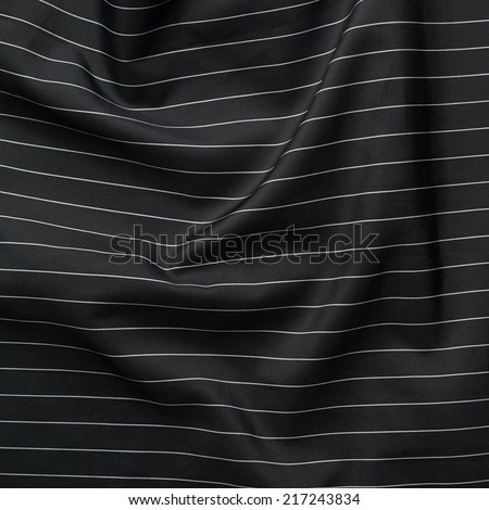 Creased black cloth material with the white thin stripes fragment as a background texture composition