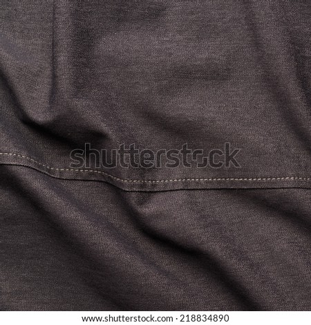 Creased black jeans cloth material fragment as a background texture composition