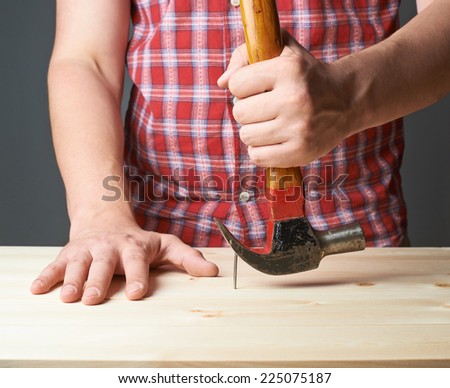 Taking out the nail from the wooden boards with the help of the hammer tool composition