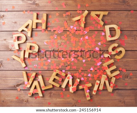 Happy Valentine\'s Day card made with the block letters and confetti over the wooden surface