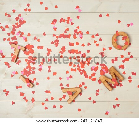 Ti Amo meaning I Love You in Italian written with the block letters covered with red heart shaped confetti over the wooden background
