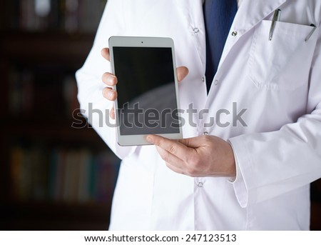Close-up fragment of a man in a white doctor\'s coat holding a pad tablet device in his hands, shallow depth of field composition
