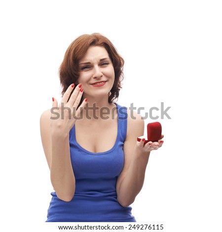 Happily surprised young caucasian woman in her twenties holding opened red wedding ring box, isolated over the white background