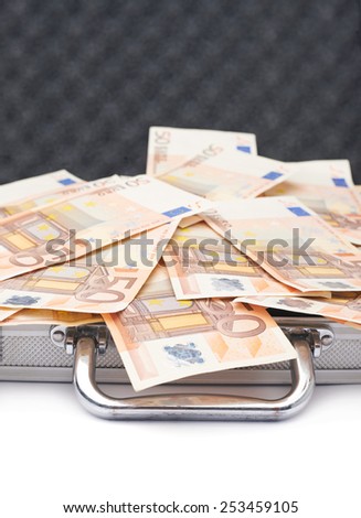 Suitcase full of fifty euro bank note bills isolated over the white background