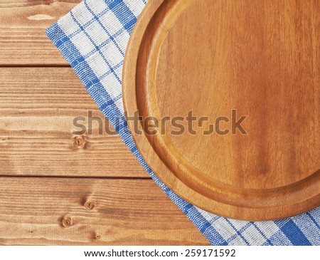 Blue tablecloth or towel over the surface of a brown wooden table with a round wooden tray on top of it
