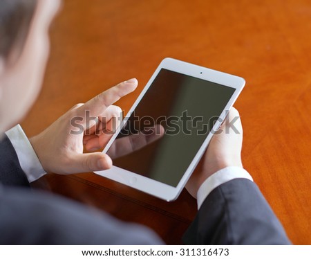 Close-up fragment of a man in a business suit working with the tablet pad device, behind his shoulder close-up composition with a shallow depth of field