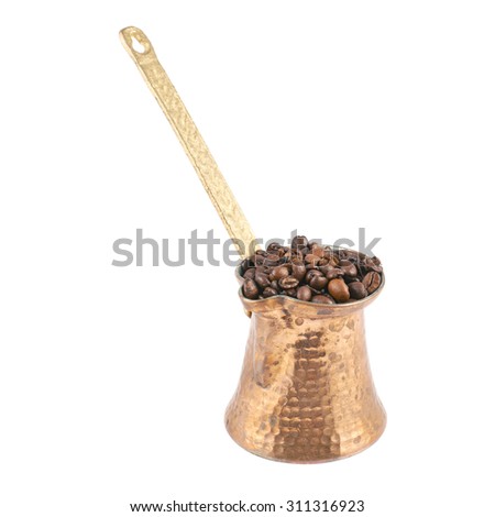 Copper cezve filled with coffee beans, isolated over the white background