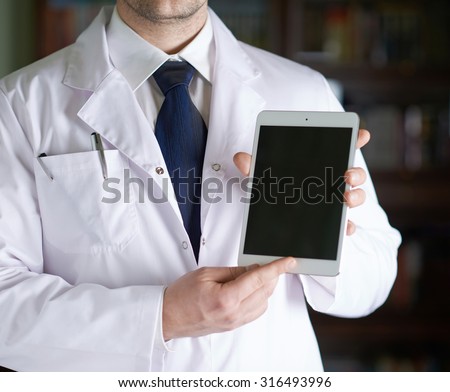 Close-up fragment of a man in a white doctor's coat holding a pad tablet device in his hands, shallow depth of field composition