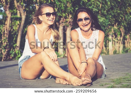 Pretty beautiful girl friends in sunglasses having fun. Both looking at camera and smiling (laughing). Concept of female friendship.