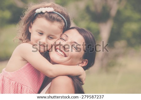 Mother and daughter playing on the grass at the day time. Concept of friendly family.