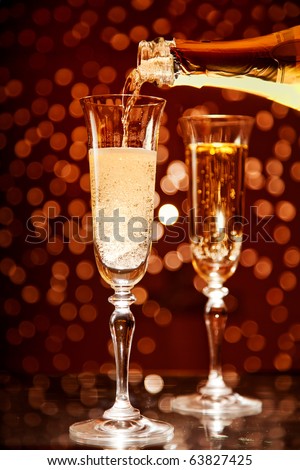 Champagne pouring into elegant glass over holiday bokeh background