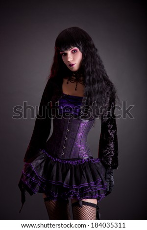 Gothic girl in purple and black outfit, studio shot on black background