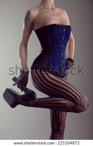 Sexy young woman wearing corset and high heel shoes, studio shot with vintage tone