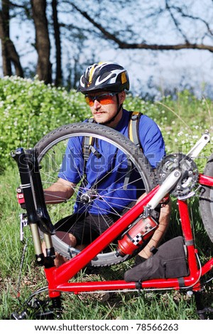 Bike repair. Young man repairing mountain bike in the forest