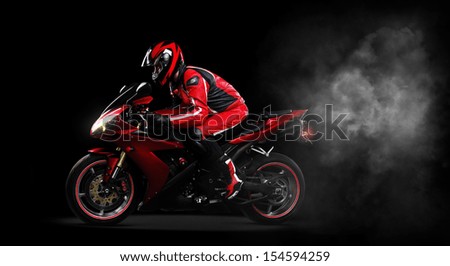 Motorcyclist in red equipment and helmet on black background side view full length