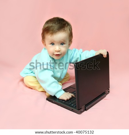 baby sitting with laptop on pink background