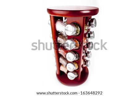 A close up on a spice rack full of a variety of different spices and herb  isolated on a white background.
