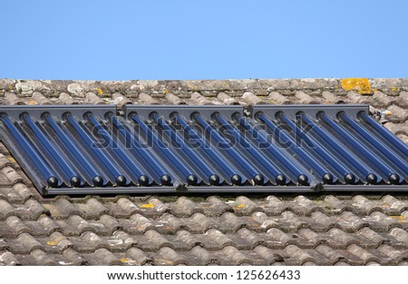 Solar glass tube hot water panel array mounted on a tiled roof