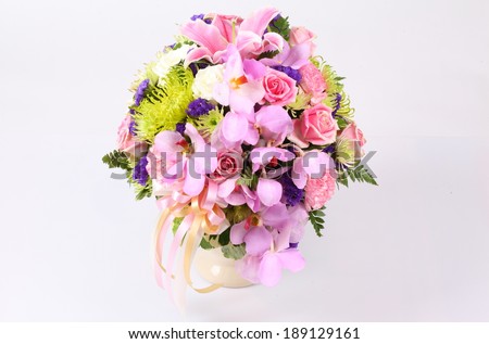 Colorful pink flower arrangement centerpiece with roses, lily, carnations, isolated on white.