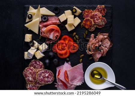Assorted starters of ham, prosciutto, salami, ham, parmesan, camembert, olives, chopped cherry tomatoes. In the center of the plate is a gravy boat filled with olive oil, inside a teaspoon. The food l Stock foto © 
