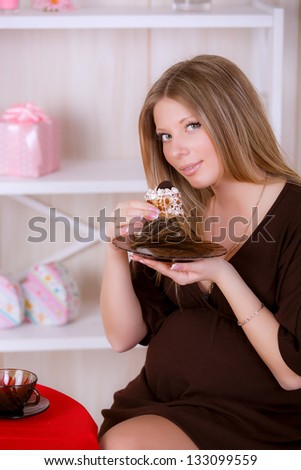 Young and beautiful pregnant woman eat cake
