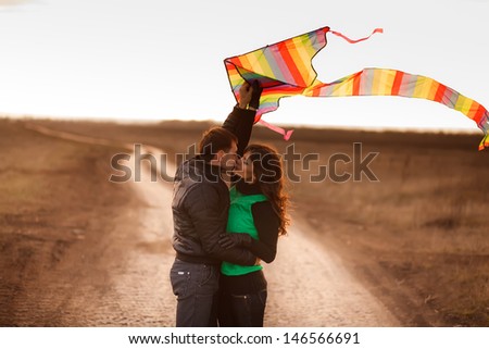 A love story. A man and a woman on autumn road running with a kite. Love and relationships. Autumn sunset.